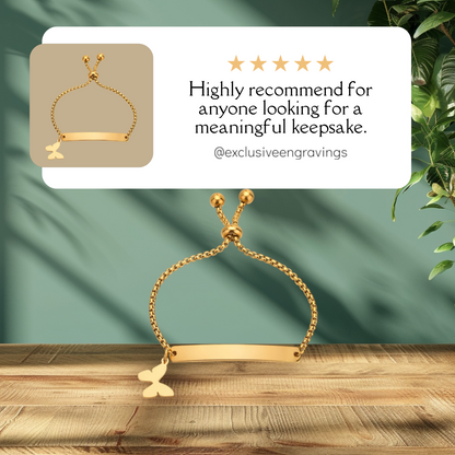 Gold bracelet with butterfly charm on a wooden surface with a green fabric background